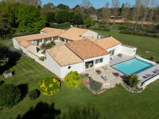 Photo aérienne de l’ensemble des gîtes de L’Hacienda avec toiture en tuiles et jardin arboré en Charente-Maritime.